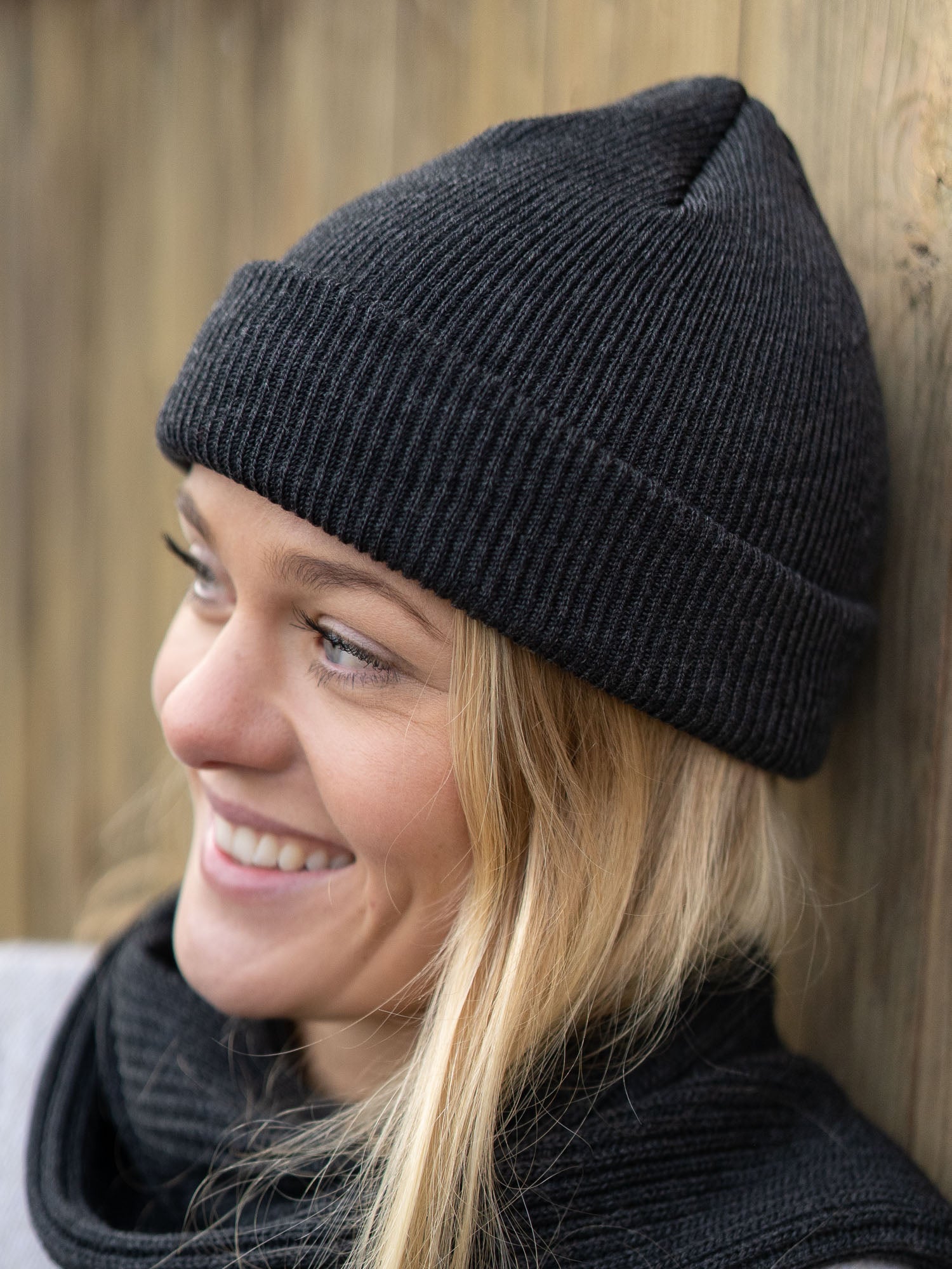 Junge, blonde Frau trägt eine nachhaltig und fair gefertigte Strickmütze von FUXBAU aus 100 % Merino Schurwolle. GOTS zertifiziert und gestrickt in Deutschland.