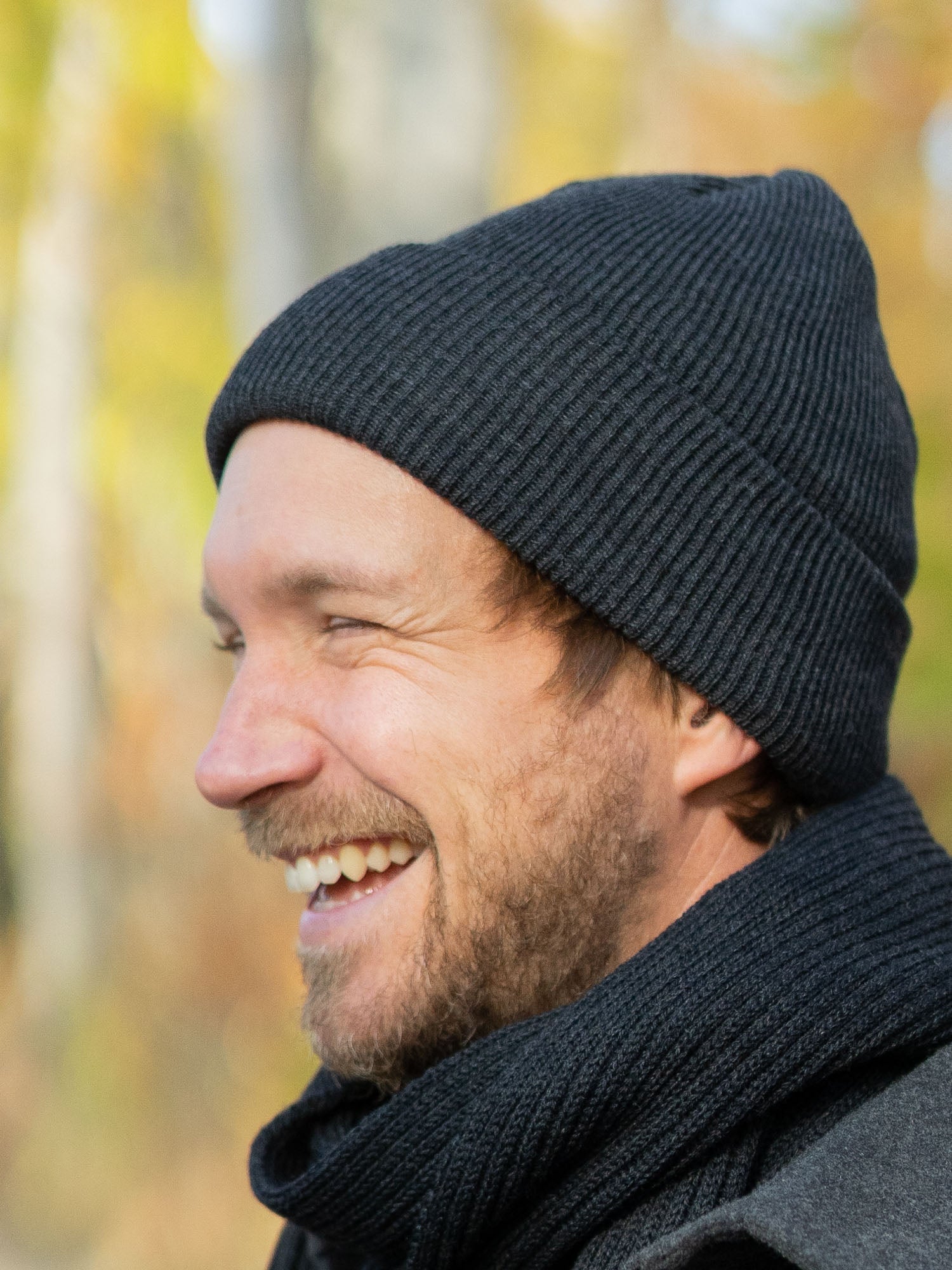 Junger, blonder Mann trägt eine nachhaltig und fair gefertigte Strickmütze von FUXBAU aus 100 % Merino Schurwolle. GOTS zertifiziert und gestrickt in Deutschland.