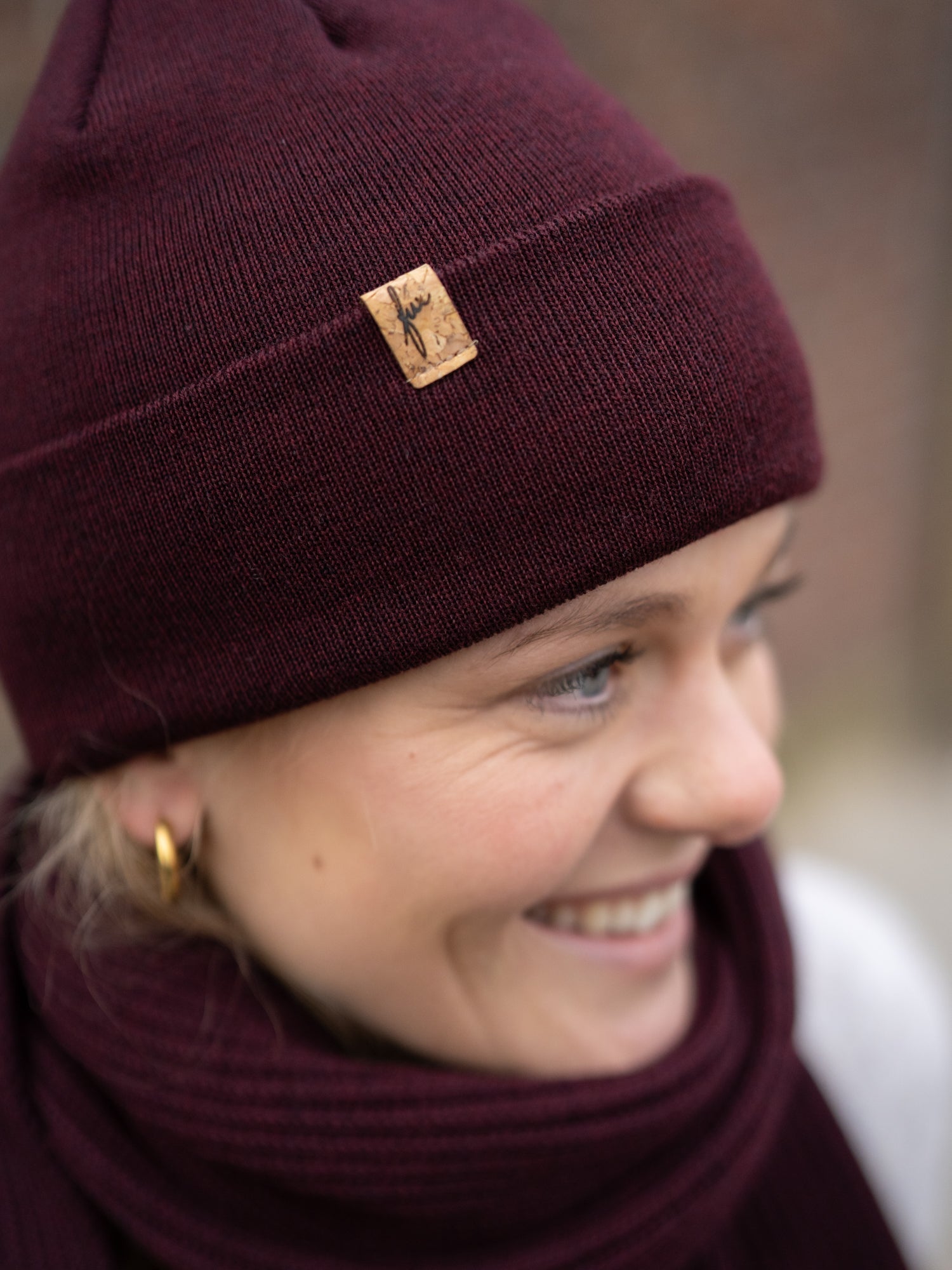 Greta trägt eine nachhaltig Fair Fashion FUXBAU Merino Kork Beanie aus Merino Schurwolle gestrickt in Deutschland in Bordeaux.