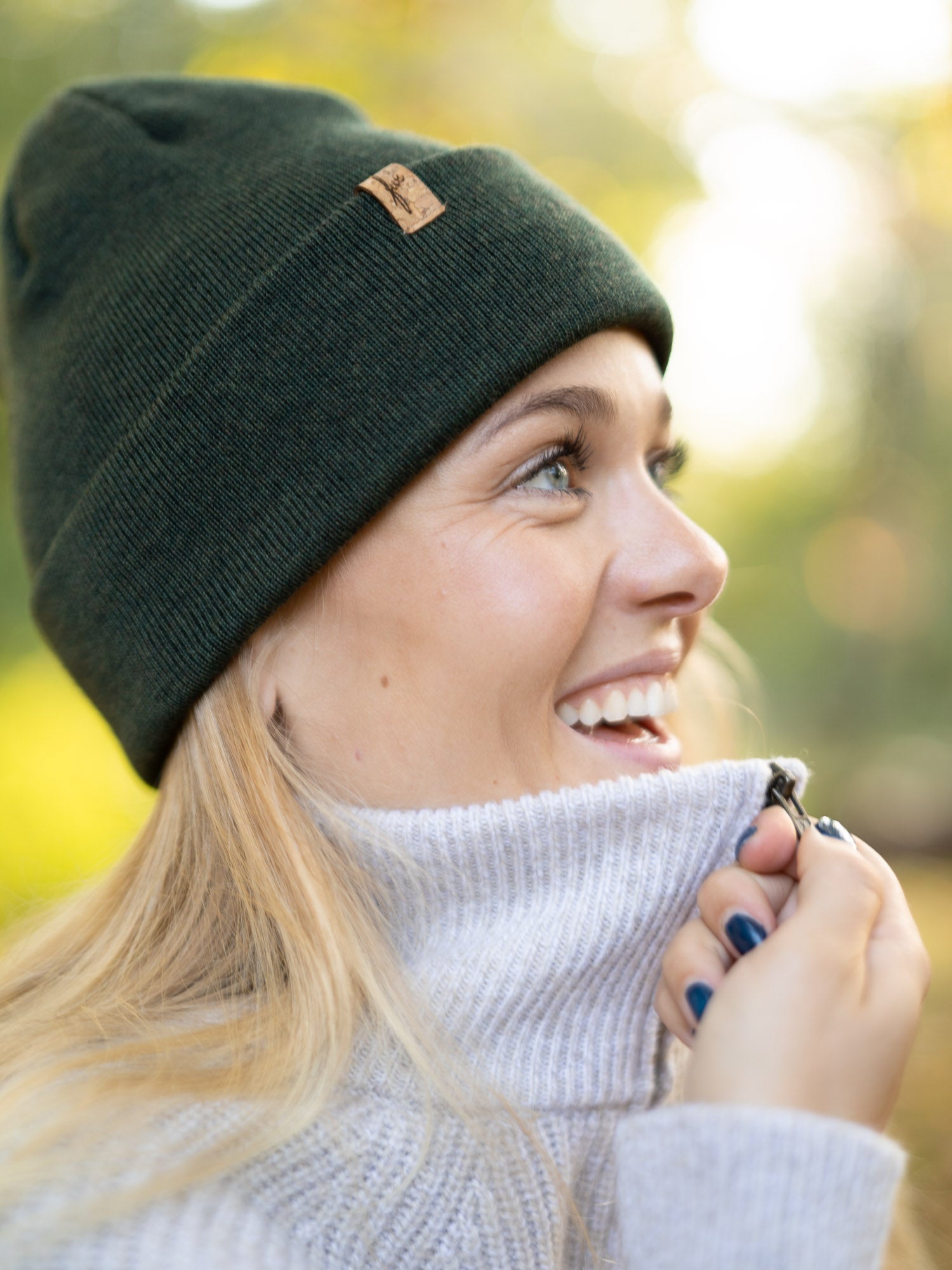 Nachhaltige Fair Fashion Merino Kork Beanie in waldgrün von FUXBAU. Getragen von einer jungen, blonden Frau im Herbst in Münster.